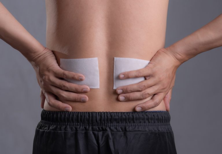 A man wears medicated back pain patches.